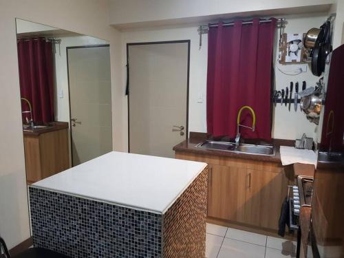 eine Küche mit einer Theke, einem Waschbecken und roten Vorhängen in der Unterkunft Mucucu's place in Manila