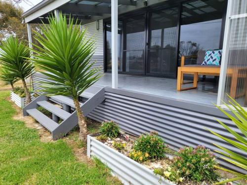 a porch with a bench on a house at Bella Blue - Scamander River Stay in Scamander