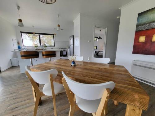 a dining room with a wooden table and white chairs at Bella Blue - Scamander River Stay in Scamander