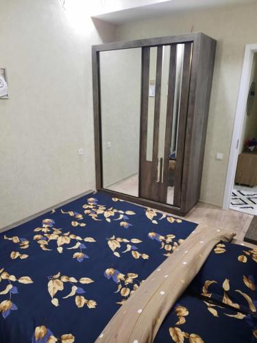 ein Schlafzimmer mit einem blauen Bett und einem Spiegel in der Unterkunft 1home in Rustawi