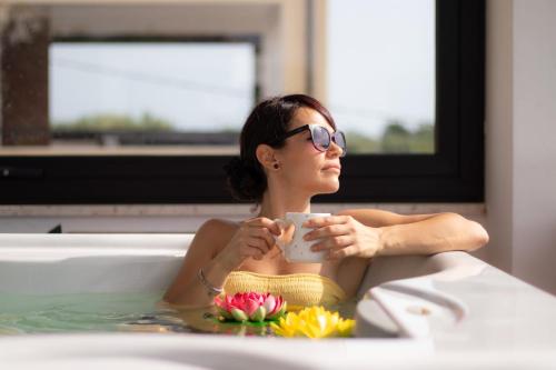 a woman in a bathtub holding a cup of coffee at Magnificat Hotel&Resort in Canosa Sannita