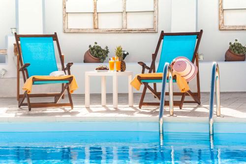 two chairs and a table next to a swimming pool at Villa Dionysus in Gennadi