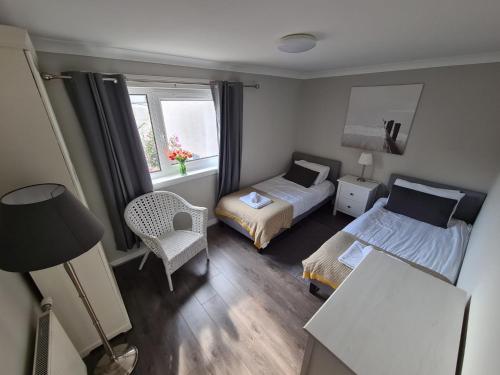 1 dormitorio con 2 camas, silla y ventana en Holyrood House, en Edimburgo