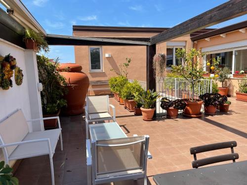 une terrasse avec des chaises blanches et des plantes en pot dans l'établissement Pellicano Guest House, à Reggio de Calabre