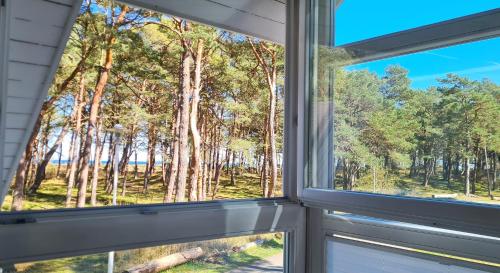 a window with a view of the woods at Strandhaus Rügen - Meerblick, Sauna, Kamin & Whirlpool in Baabe