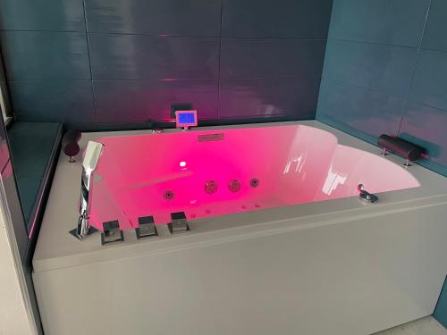 La salle de bains est pourvue d'une baignoire rose. dans l'établissement appartement luxe balnéothérapie au village naturiste du cap d'agde, au Cap d'Agde