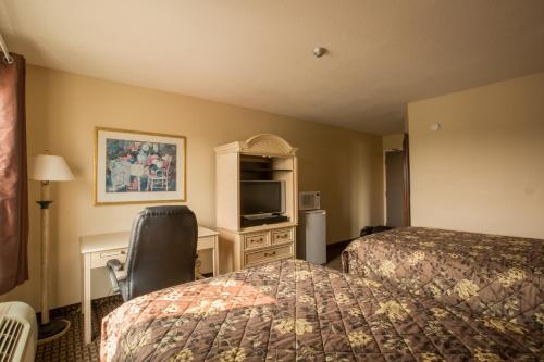 Habitación de hotel con 2 camas, escritorio y TV. en The Village Inn, en Elora