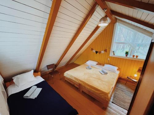 a attic room with two beds and a window at Energetikas • nameliai prie jūros in Šventoji