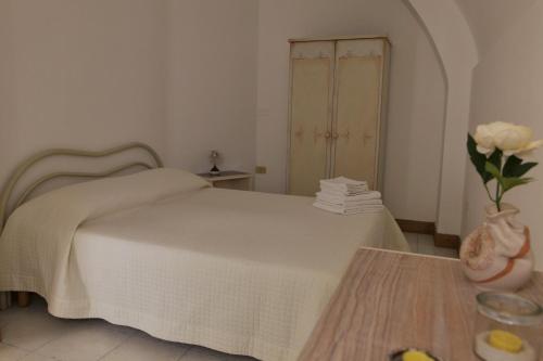 Un dormitorio con una cama y una mesa con un jarrón de flores en CASA FIORE, en Corigliano d'Otranto