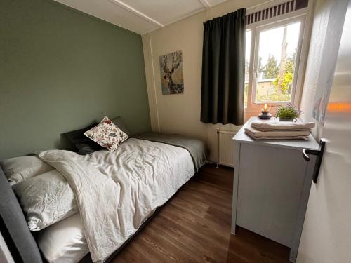 a small bedroom with a bed and a window at Fijne plek met eigen bos 2000m2 en GRATIS linnen en handdoeken!! in Denekamp