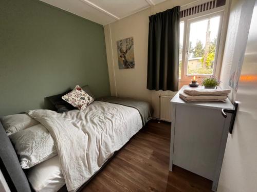 een kleine slaapkamer met een bed en een raam bij Fijne plek met eigen bos 2000m2 en GRATIS linnen en handdoeken!! in Denekamp