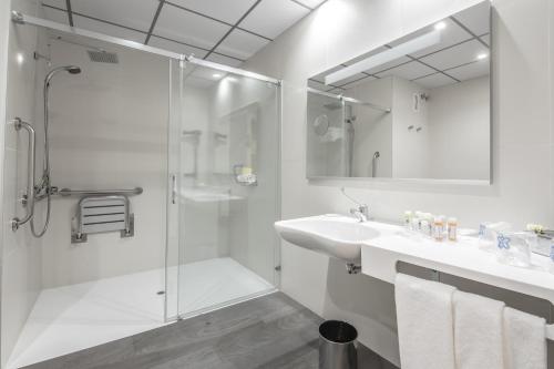 a white bathroom with a shower and a sink at Hotel Monte Puertatierra in Cádiz