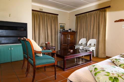 a living room with a desk and chairs and a bed at Landskroon Cottage in Paarl