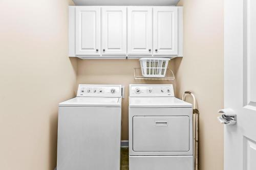 a kitchen with white cabinets and a washer and dryer at Crow Creek Perch in Calabash