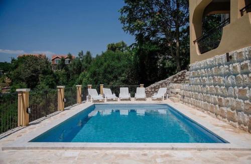 une piscine avec des chaises longues et une piscine dans l'établissement Apartments Casa Bella, à Kotor