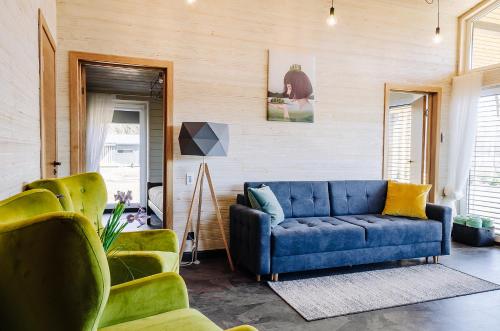 a living room with a blue couch and two chairs at Holiday Houses LILLE`S with sauna in Alūksne