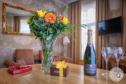 uma garrafa de champanhe e um vaso de flores sobre uma mesa em Bariseele B&B em Bruges