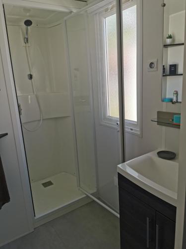 une salle de bain blanche avec une douche et un lavabo dans l'établissement MOBIL HOME SERENITE 2CH VALRAS PLAGE, à Valras-Plage