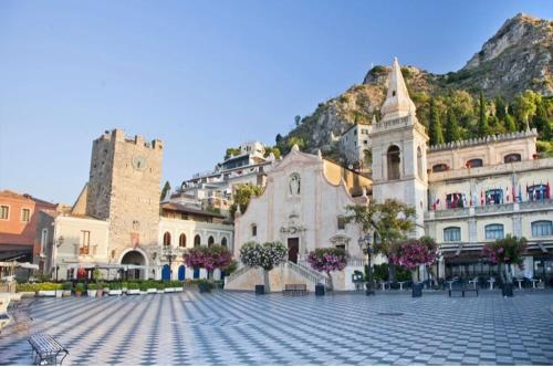 een groot gebouw met een berg op de achtergrond bij LA VELA RECANATI in Giardini Naxos