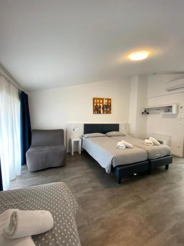 a bedroom with two beds and a chair at Hotel Aurora & Appartamenti in Nago-Torbole