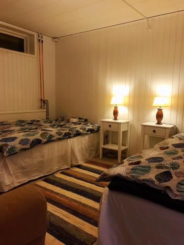 two beds in a room with two tables and two lamps at Centralt och havsnära med utsikt mot pool in Kalmar