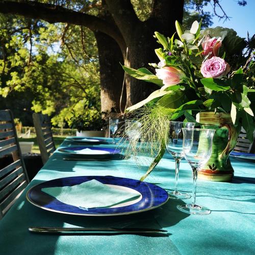 a table with plates and glasses and a vase of flowers at La Bastide du Capelier - Chambres d'hôtes avec baignoire balnéothérapie - 3 étoiles in Salernes