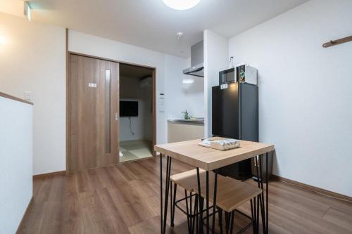 a kitchen with a small table and a refrigerator at HANASTAY花渓居 · 澄（KIYOSI) in Osaka