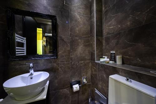 a bathroom with a sink and a mirror at Gallery Art Hotel in Tríkala