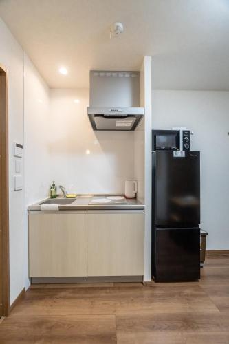 a kitchen with a black refrigerator and a sink at HANASTAY花渓居 · 澄（KIYOSI) in Osaka