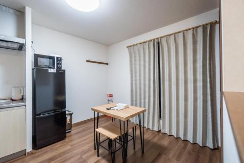 a small kitchen with a table and a refrigerator at HANASTAY花渓居 · 澄（KIYOSI) in Osaka
