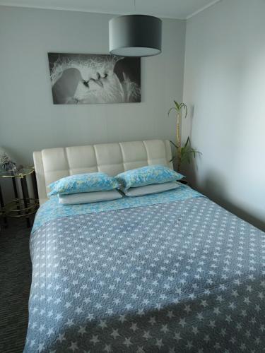 a bedroom with a bed with a blue and white blanket at Puikus apartamentai in Alytus