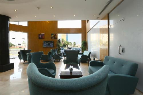 a waiting room with blue chairs and tables and windows at Quiet Dreams - King Road Branch in Jeddah