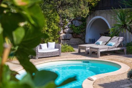 una piscina in un cortile con due sedie e un tavolo di La Bastide d'Antoine a Saint-Tropez