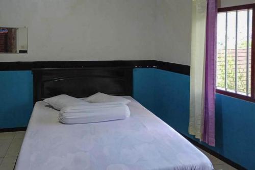 a bed with two pillows on it next to a window at Villa Ghazani 4 at Desa Wisata Songgokerto in Songgoriti