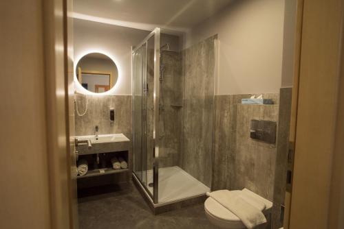 a bathroom with a shower and a toilet and a sink at Hotel Civitas in Sopron