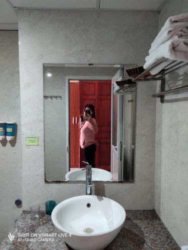 a woman taking a picture of a sink in a bathroom at Khách sạn NHẬT MINH Cửa Lò in Cửa Lò