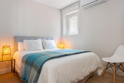 a white bedroom with a bed and a window at Plaza España, acogedor apartamento con patio by OUTIN in Seville