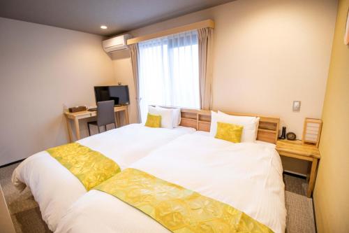 a bedroom with a large bed with white sheets and yellow pillows at Stay SAKURA Kyoto Kiyomizu Gojo in Kyoto
