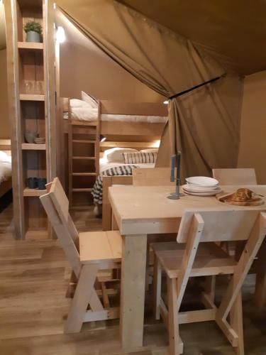 einen Tisch und Stühle in einem Zimmer mit Etagenbetten in der Unterkunft Tente Familiale au Camping Hautoreille in Bannes