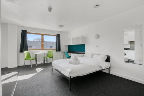 a white room with a bed and a table and chairs at Bright & Central Studio in Luton, Sleeps 2 in Luton