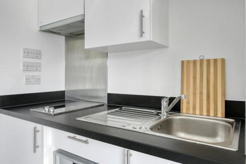 a kitchen with a sink and white cabinets at Bright & Central Studio in Luton, Sleeps 2 in Luton