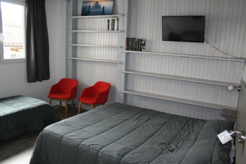 a bedroom with a bed and two red chairs at Hôtel Le Relais Dax in Dax