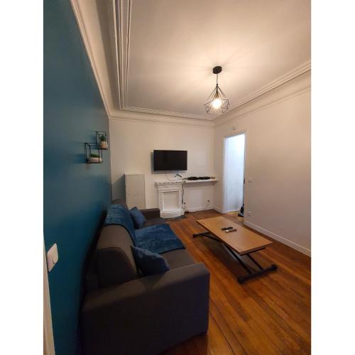 a living room with a couch and a tv at Un appartement authentique à deux pas de Paris . in Saint-Mandé