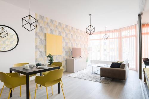 a living room with a table and yellow chairs at Parizs Garden Apartments in Debrecen