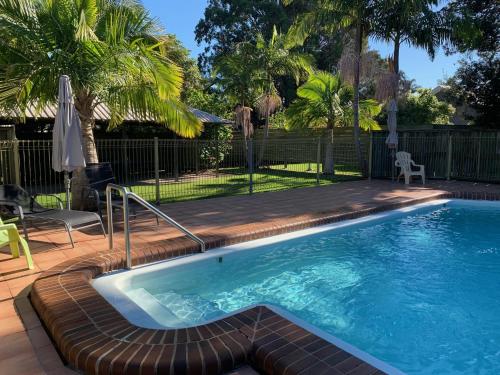 a large swimming pool with a wooden deck and a swimming pool at Sunny, 2-bedroom apartment with pool, 200m from Caseys beach in Batehaven
