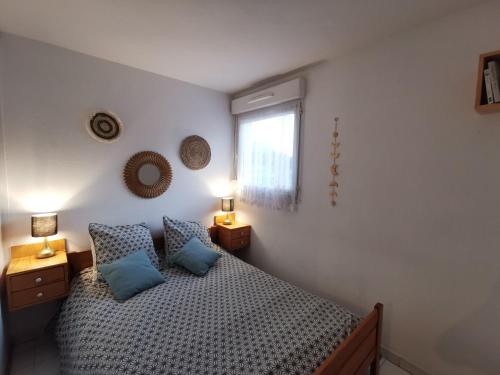 a bedroom with a bed with blue pillows and a window at Appartement T2 en résidence, centre ville d'Embrun in Embrun