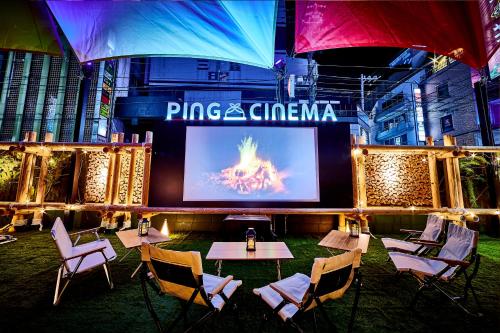 a stage with tables and chairs in front of a screen at Hotel BaliAn Resort Shinjuku Glamping in Tokyo