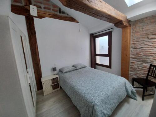 1 dormitorio con cama y pared de ladrillo en Apartamento en el Casco Histórico de Plencia, en Plentzia