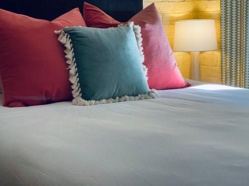a bed with pink and blue pillows and a lamp at The Shopkeepers Quarters in Tenterfield