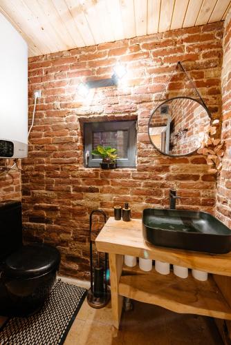 a bathroom with a black sink and a brick wall at Sweet Escape Vlădeasa in Rogojel